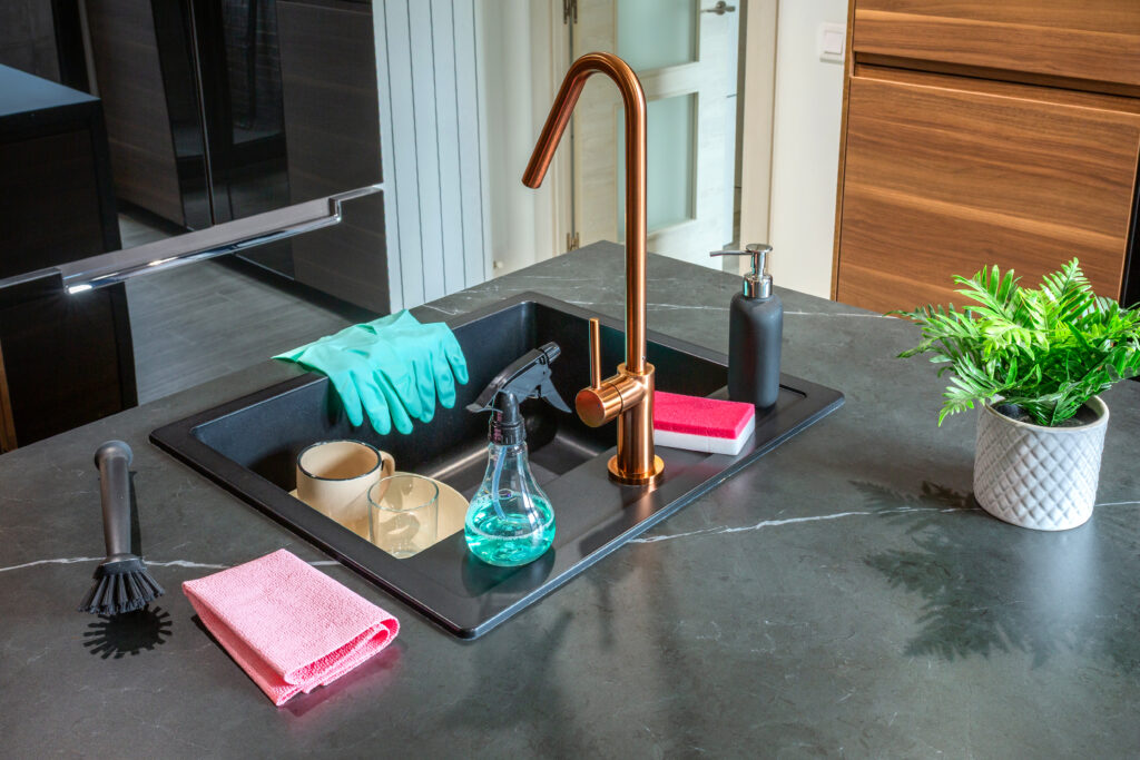 Cleaning products and equipment placed near sink on empty kitchen